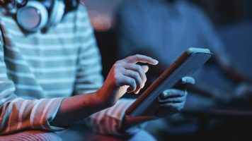side-view-woman-home-using-headphones-tablet